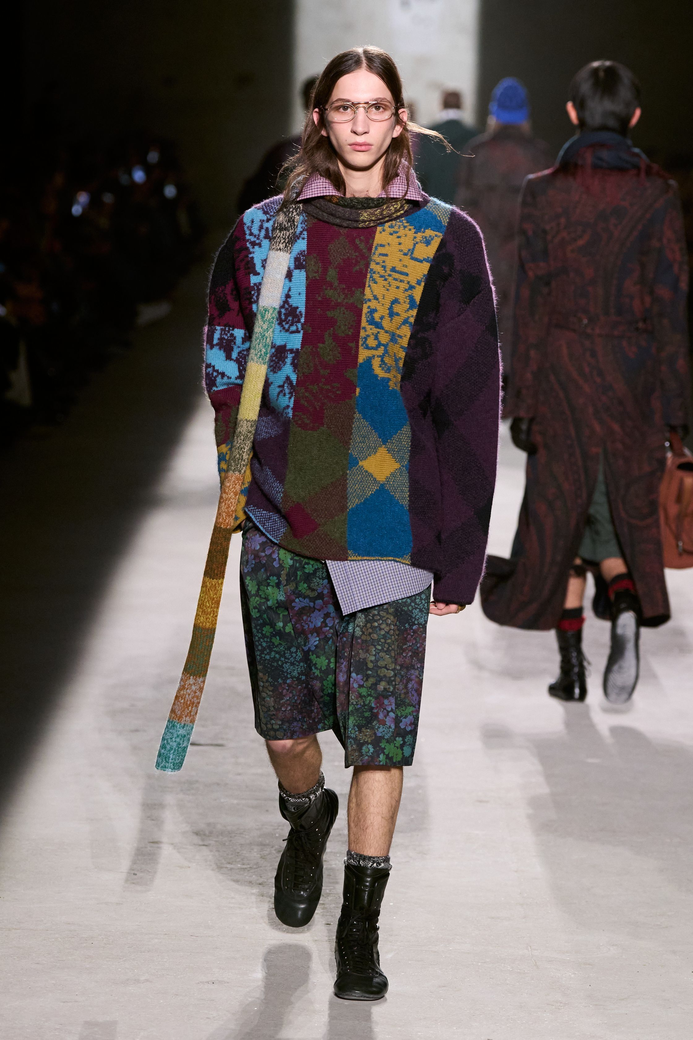 Dries Van Noten 2026秋冬以高度成熟的综合色彩与织物语言，继续书写其标志性的“文化层叠美学”。民族图案针织、拼接围巾、军装轮廓与优雅大衣在行走中形成复杂而克制的视觉节奏，色彩看似丰富却始终维持理性秩序。这是一种属于思想型穿着者的浪漫，不依赖情绪爆发，而通过织物、比例与色块的精密组合，构建出安静却极具深度的男性诗意-顽石频道趋势研究